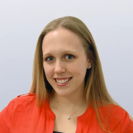 Picture of Brie Engelson smiling in an orange shirt with a thin necklace
