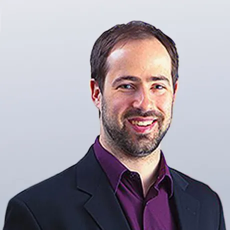 Picture of Pierre-Luc Soucy smiling with a black blazer and a deep purple collared shirt open at the neck