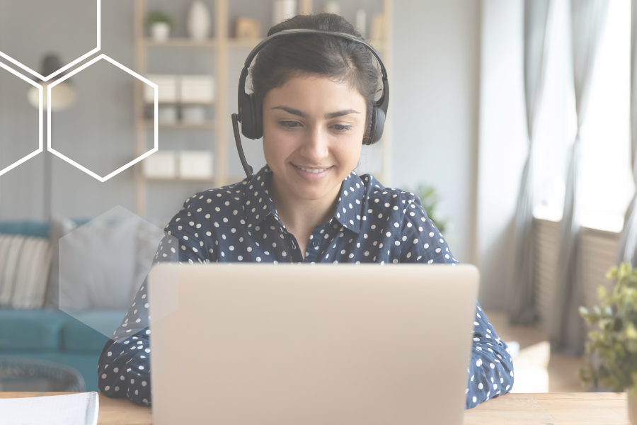 Woman typing with headset on behind laptop
