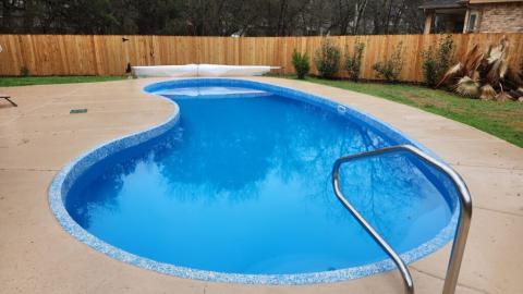 renovated fiberglass pool that is blue with tan pool deck