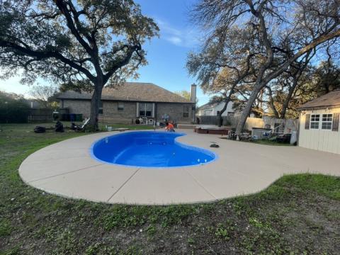 bright blue fiberglass pool with tan concrete pool deck