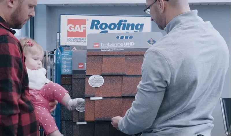 man showing another man with his daughter a roofing sample