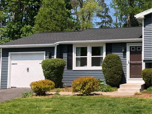 blue-gray home with white trim and dark roof