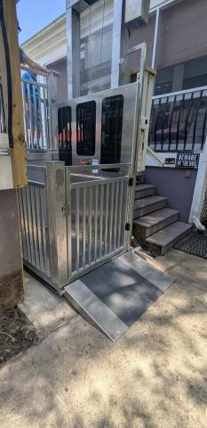 An outdoor wheelchair lift next to steps leads to an elevated porch entrance.