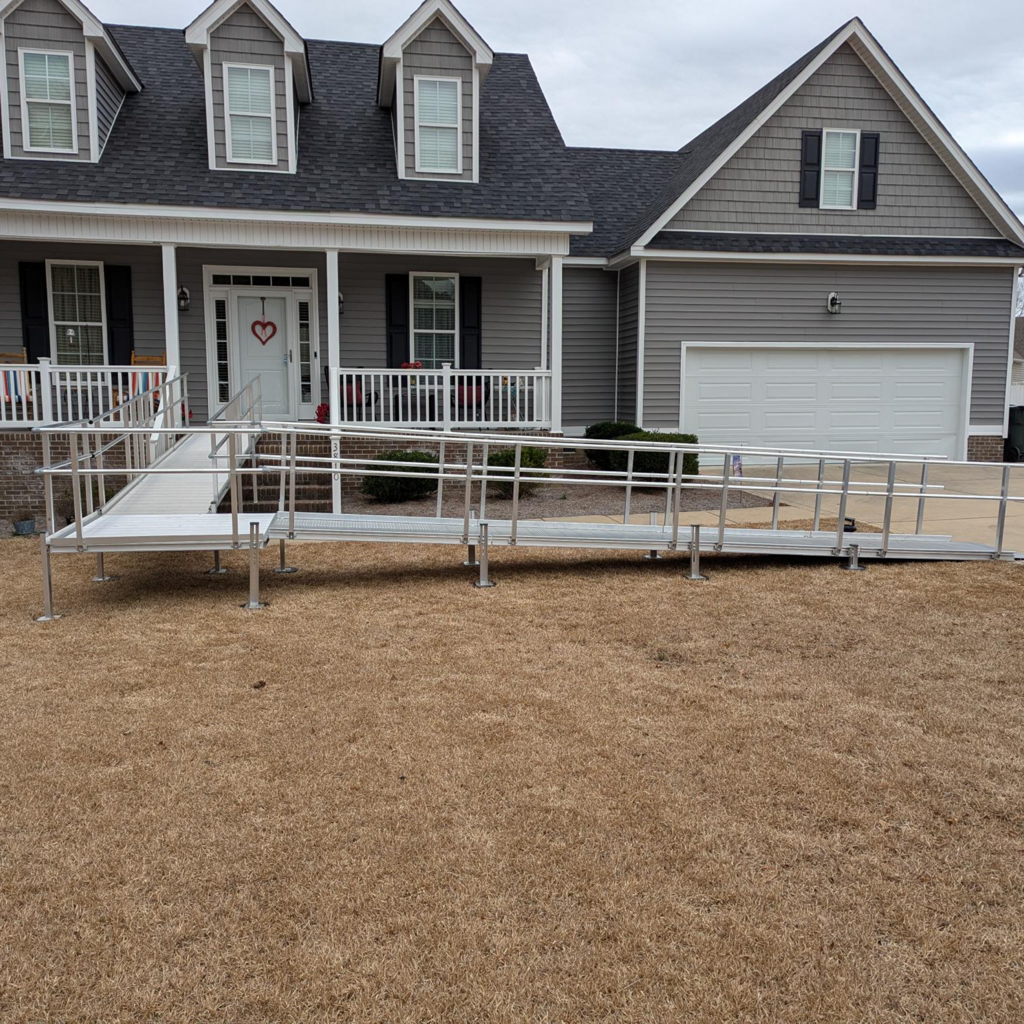 A home with a metal wheelchair ramp leading to the front porch and door.