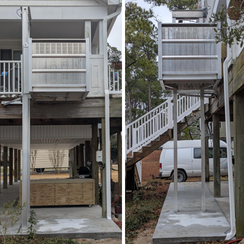 A small outdoor home elevator with metal rails and platform next to a staircase and driveway.