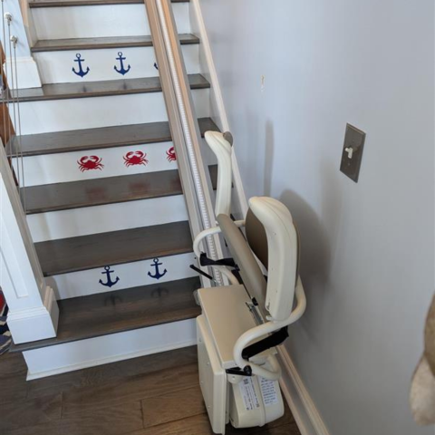 A stairlift beside stairs decorated with blue anchors and red crabs on each steps riser.