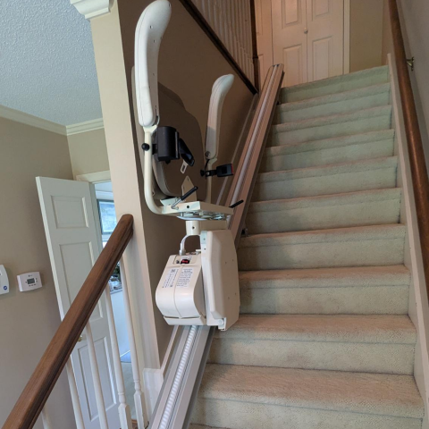 A stair lift is installed along a carpeted staircase in a residential home.