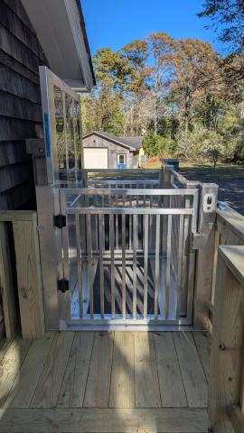 Aluminium wheelcair lift in the upright positon connected to a wooden porch