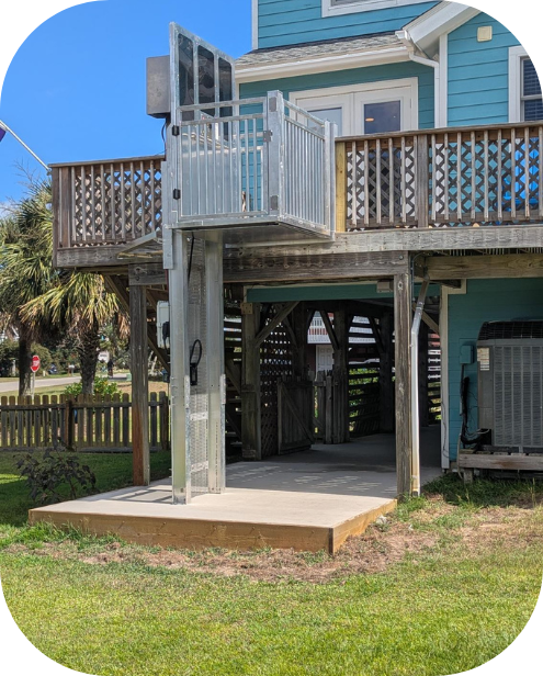 Outdoor residential wheelchair lift next to a porch, attached to a two-story house.