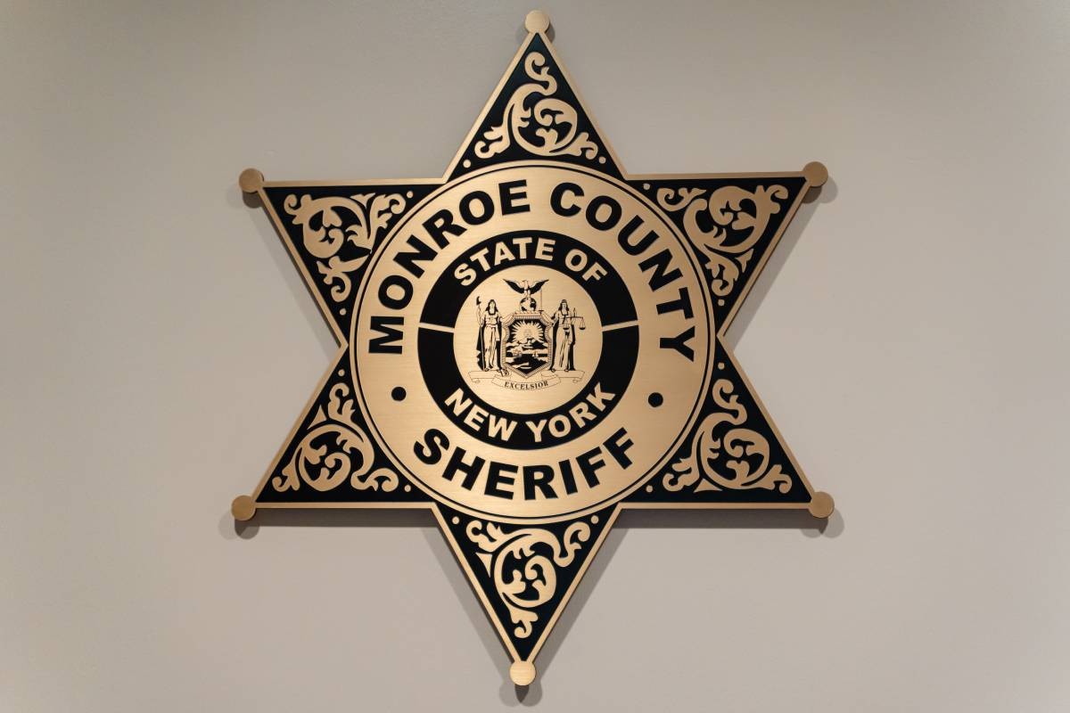a black dog interacts with a sheriff and a woman at the Monroe County Sheriffs office