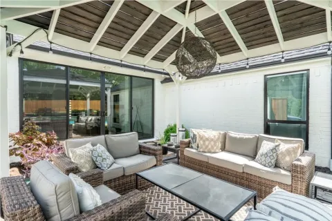 covered patio with wicker furniture, cushions, glass table, and string lights