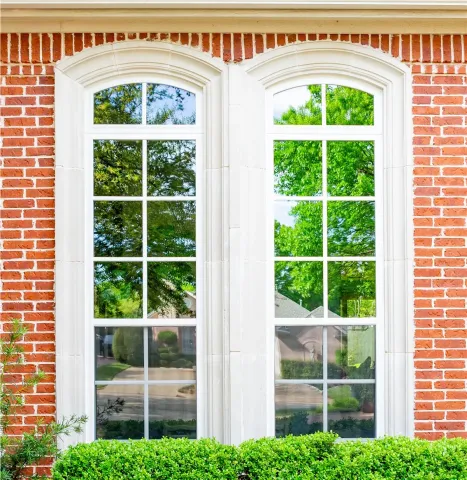 two arched white trim windows on a red brick wall