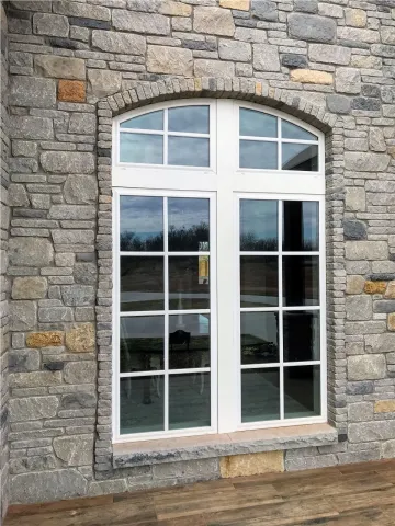white arched window with grid panes set in a stone wall