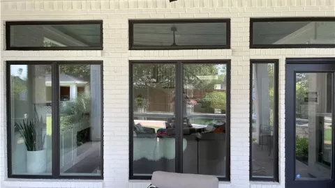 white brick house exterior with large black-trim windows and glass door