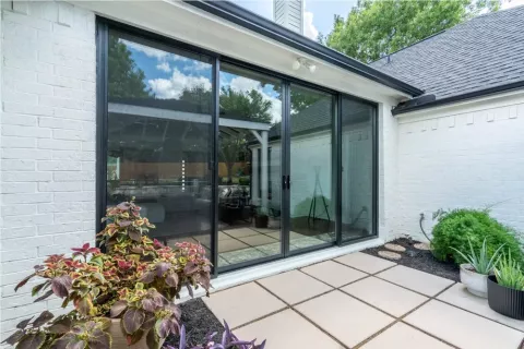 large sliding glass doors open to patio with potted plants and square tile flooring