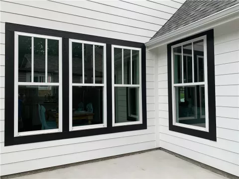 white house exterior with three large black-trimmed windows and one black-trimmed corner window
