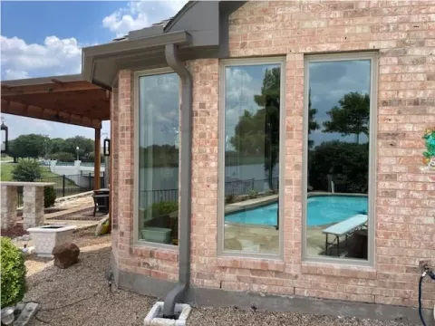 two large windows reflect a backyard pool and trees