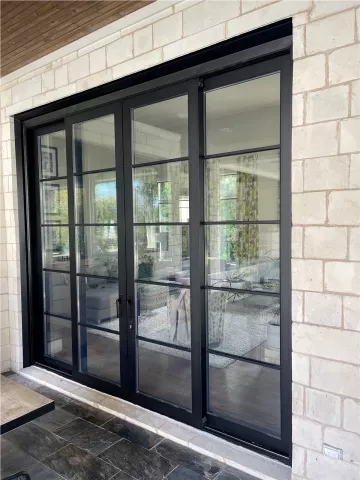 black-framed sliding glass doors set in a light stone wall