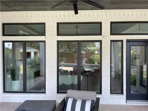 large windows and glass door with black frames on a white brick wall