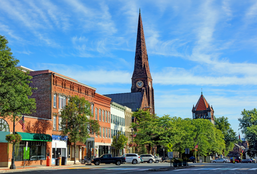 small town tree-lined street with clock tower and brick buildings
