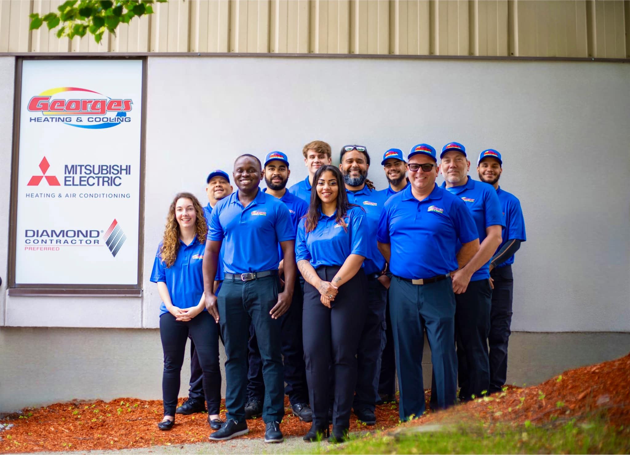 Georges Heating & Cooling family and staff photo in front of fleet vehicles