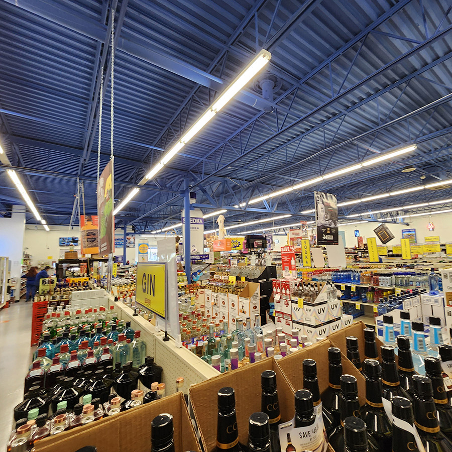 liquor store interior with various bottles and colorful signs under a blue ceiling