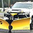 white truck with a large yellow snow plow attachment in the front