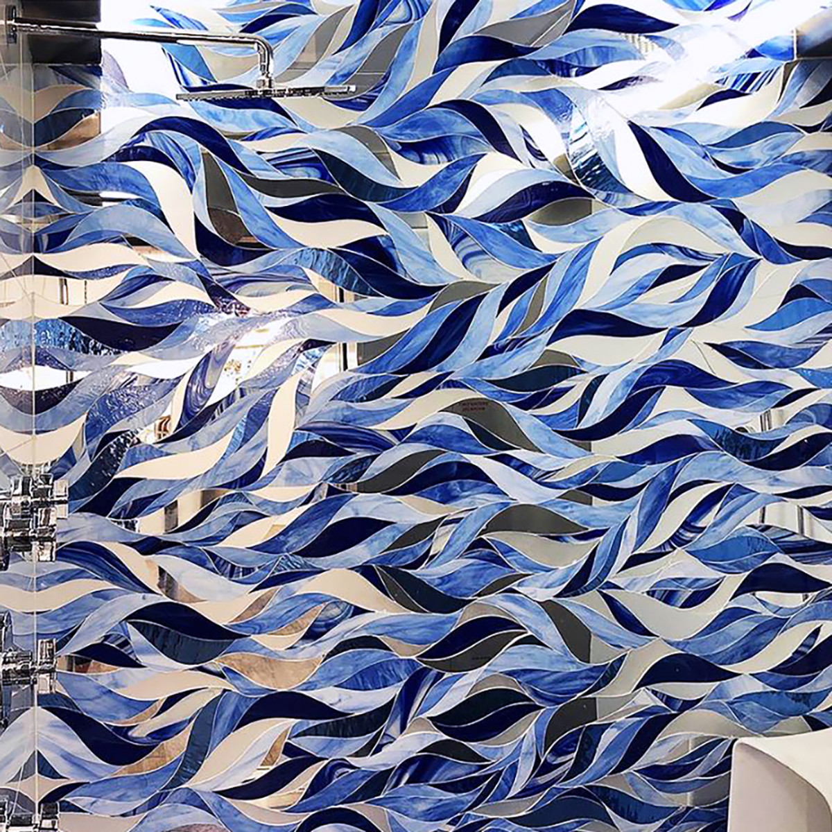 A beautiful wavey blue moasic on a bathroom wall.