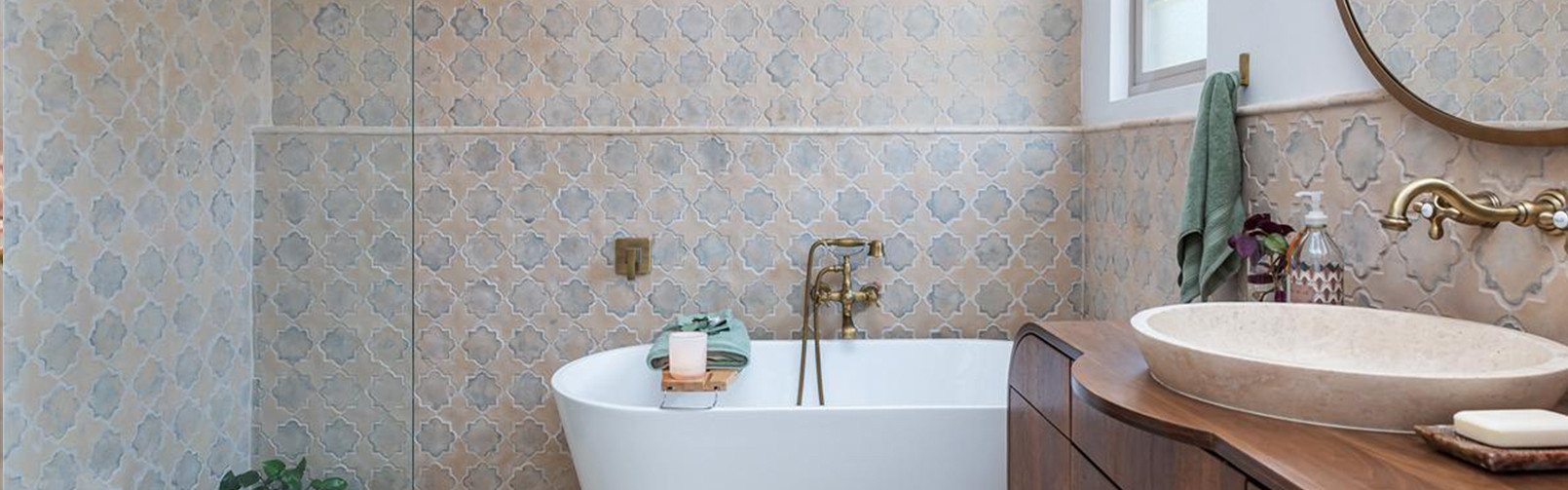 Bathroom with patterned tile walls, a freestanding tub, round mirror, and modern sink.