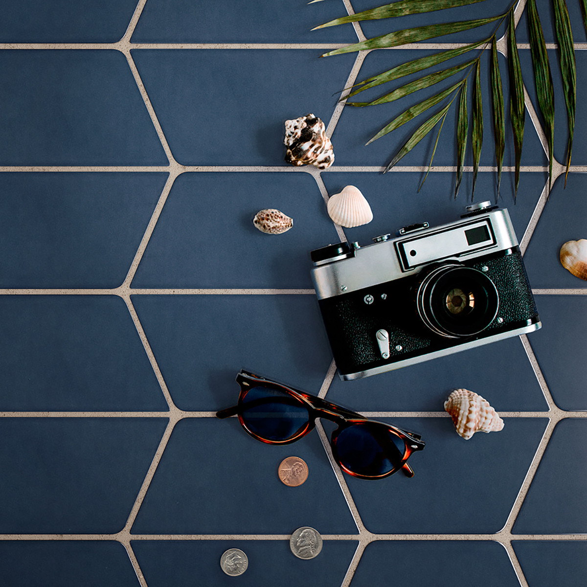 navy ceramic tile with camera sunglasses shells coins