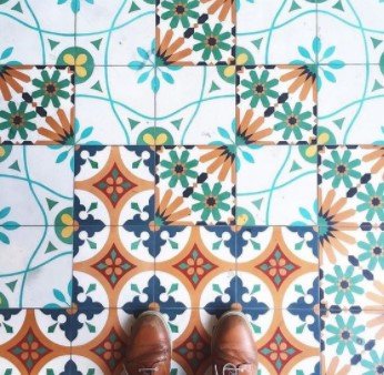 Brown shoes on colorful, patterned floor tiles in blue, green, orange, and white designs.