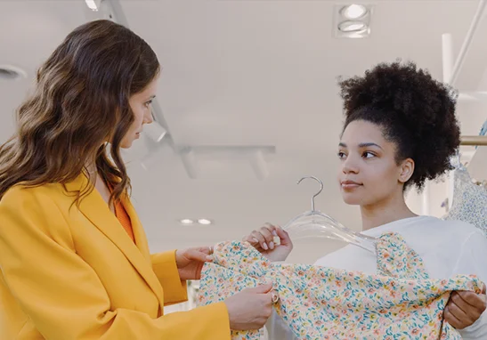 Two women discussing a floral dress in a clothing store.