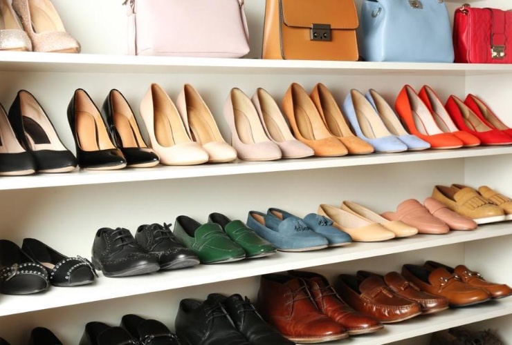 Shelves displaying assorted women’s high heels, men’s shoes, and handbags in various colors.