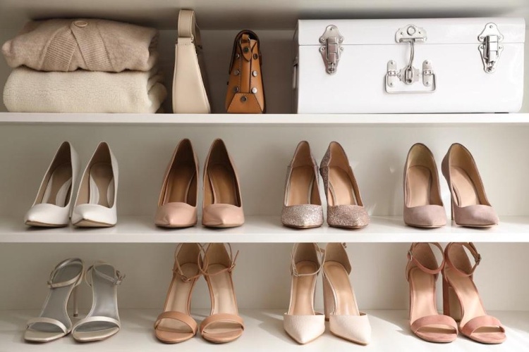 Neatly organized shelves with folded clothes, bags, and various pairs of womens high heel shoes.