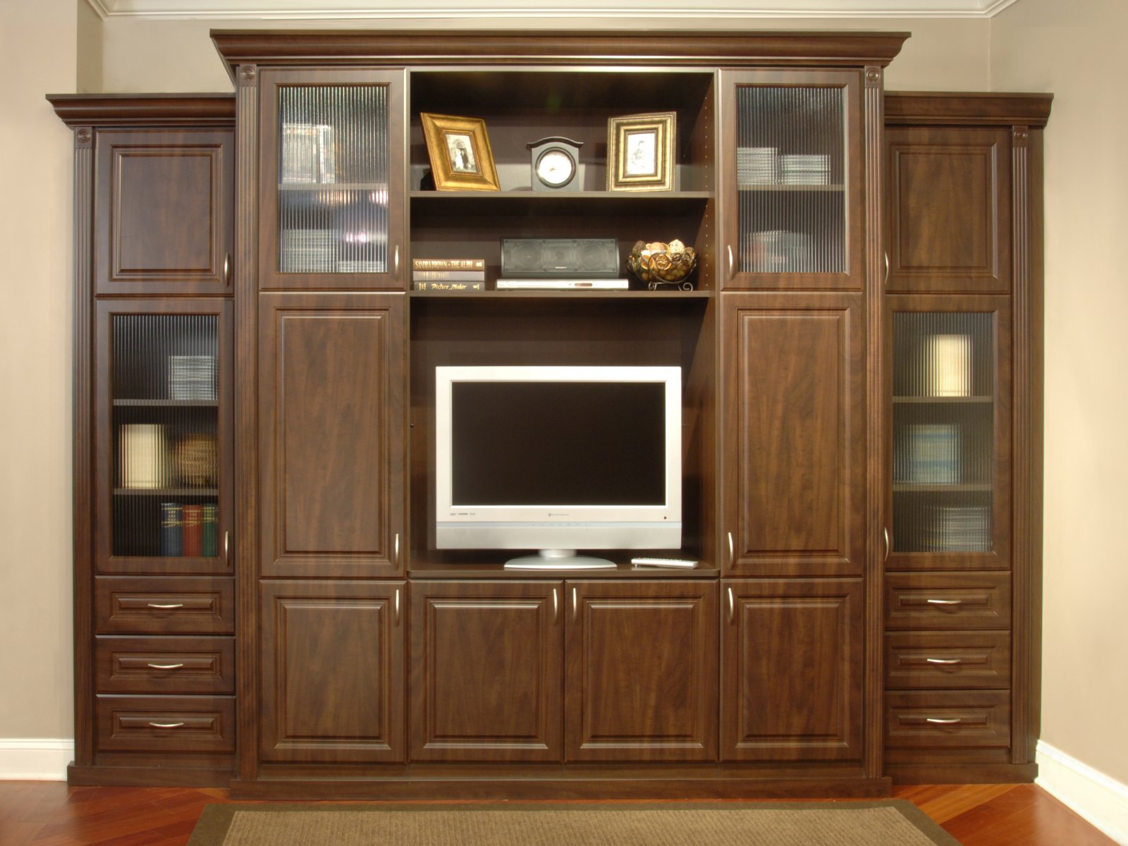 Wall unit with dark wood cabinets, a TV, books, framed photos, and decorative items displayed.