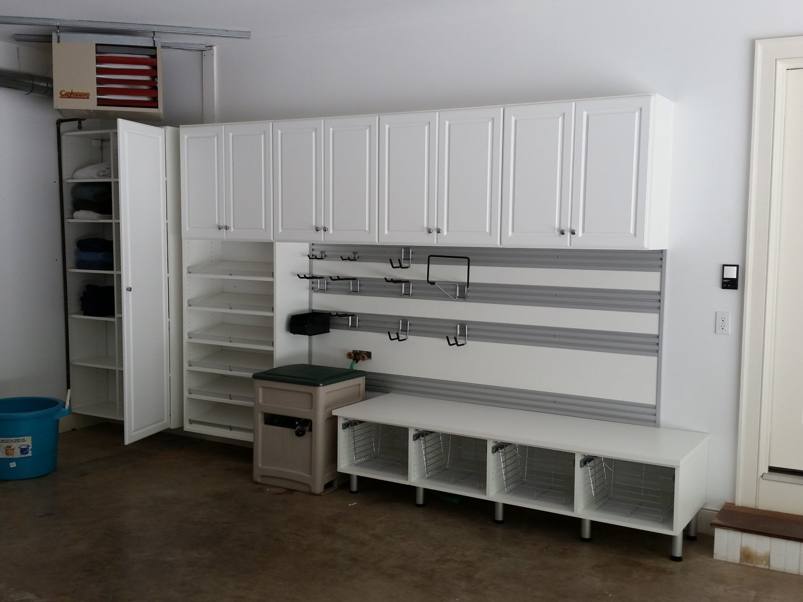 White garage storage cabinets, shelves, hooks, and bins organized against a clean wall.