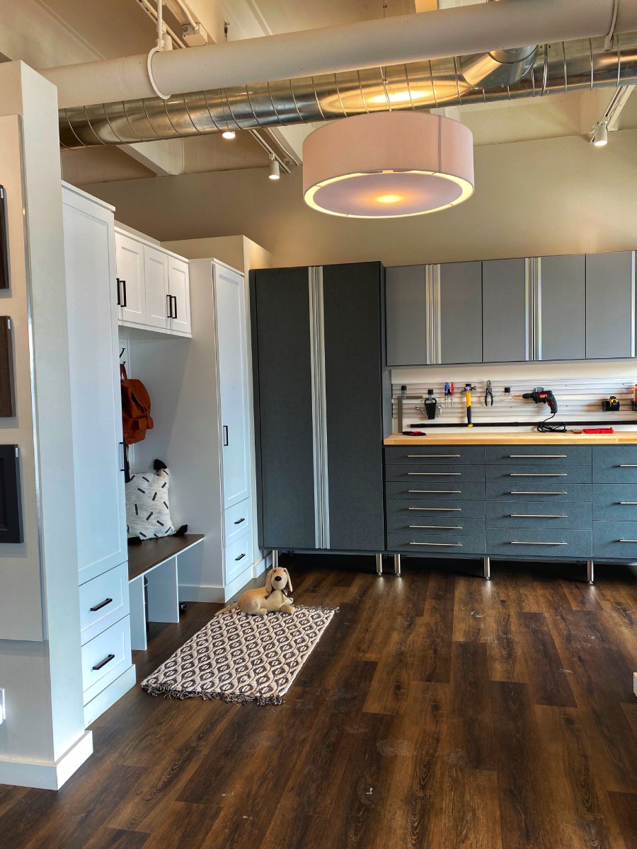 Modern, organized mudroom and workspace with cabinets, bench, tools, and a dog toy on a rug.