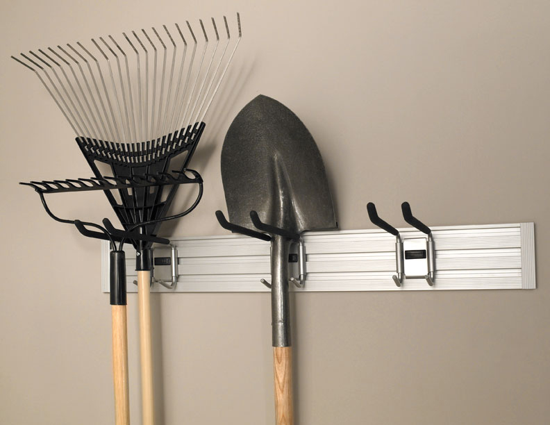 Garden tools, including rakes and a shovel, hang neatly on a wall-mounted storage rack.