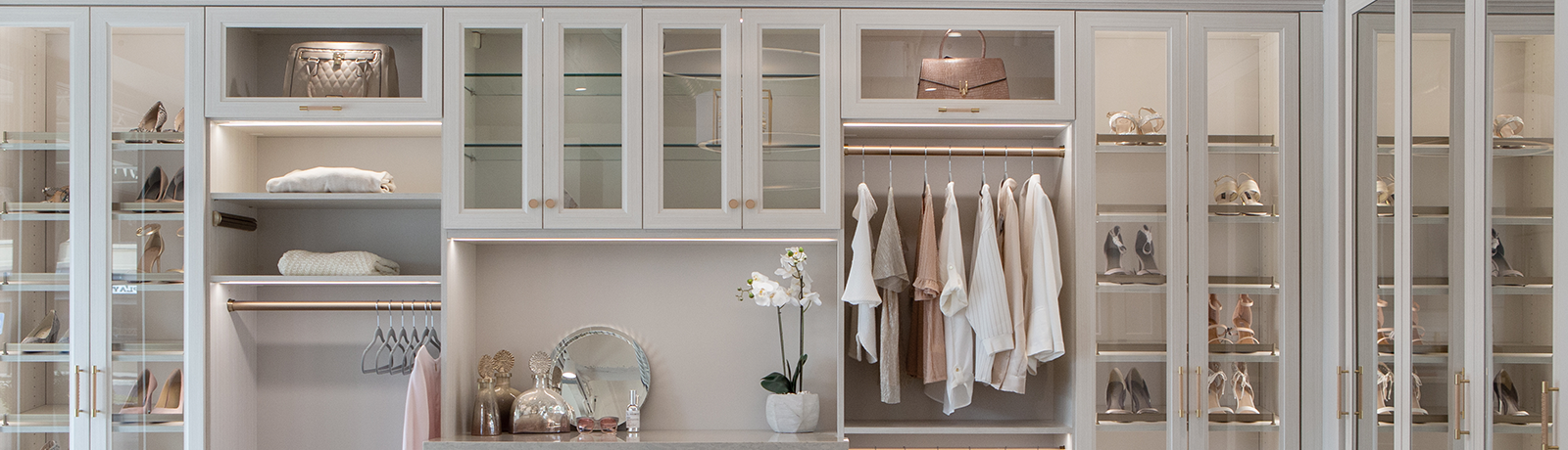 Custom walk-in closet showroom in Rochester NY with modern shelving and glass doors