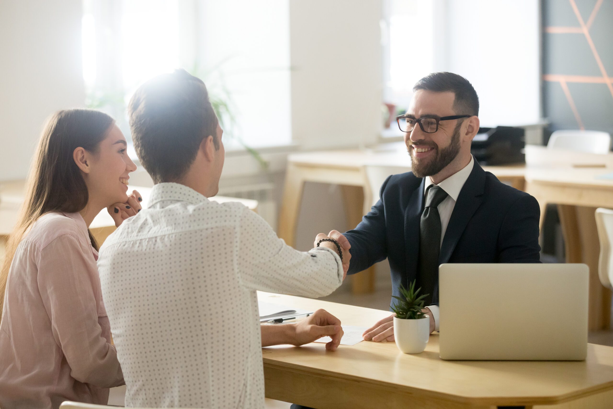 A man and woman shake hands across a table.