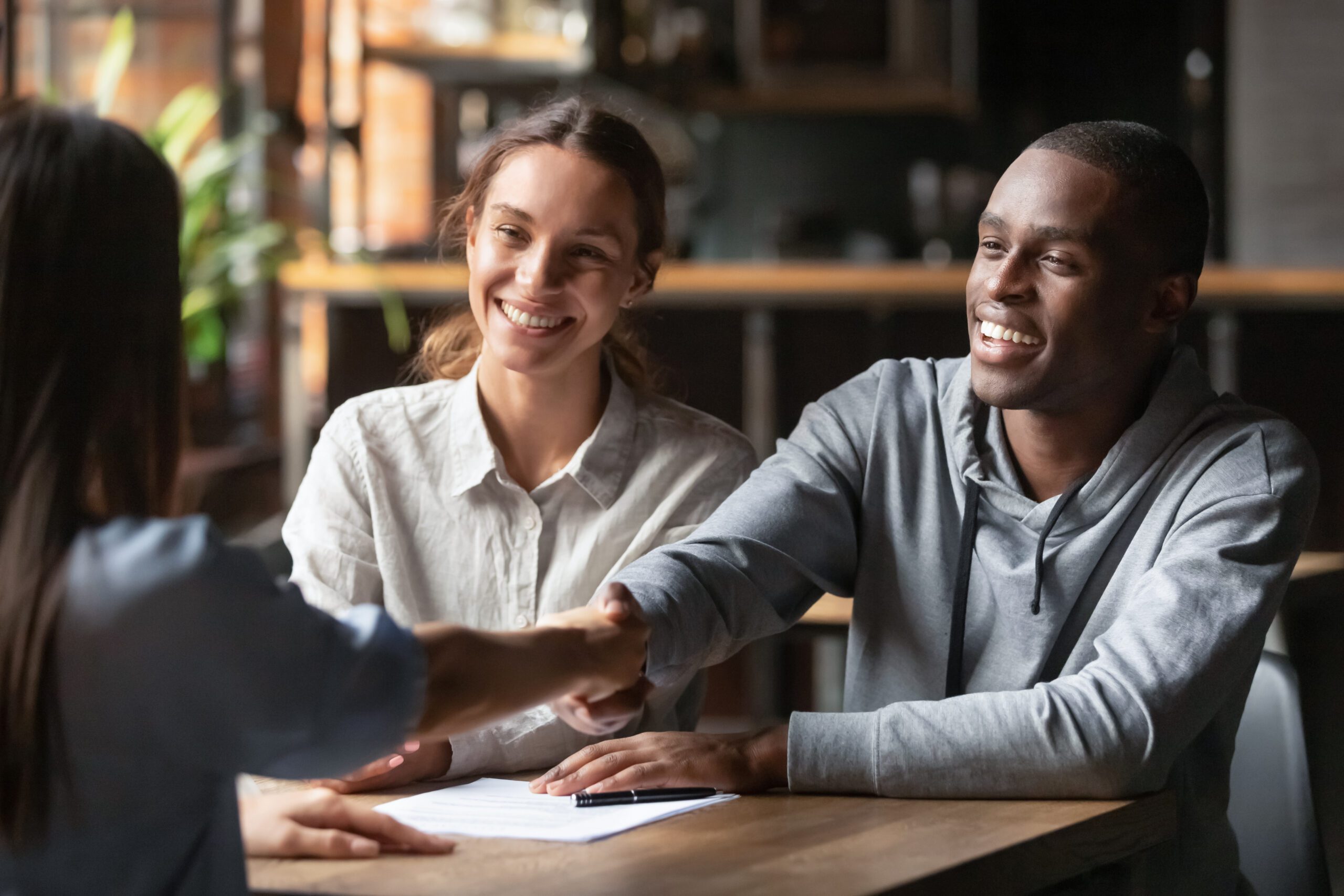 A man and a woman shaking hands across a table.