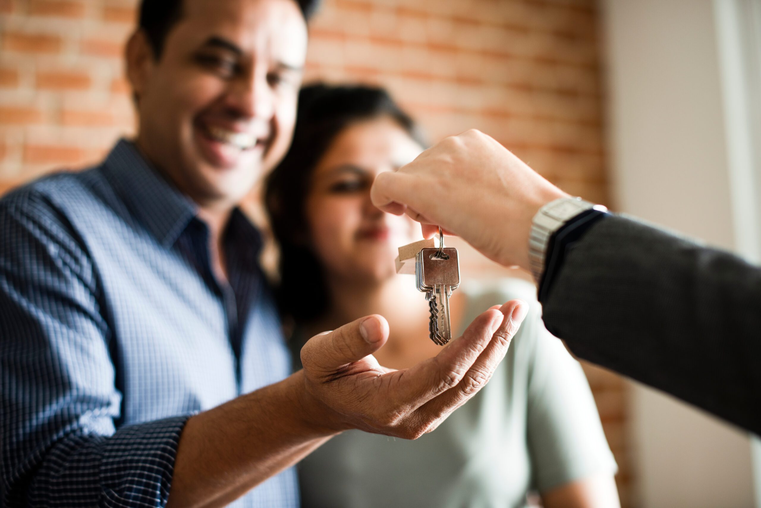 A man handing a woman a key to a house.