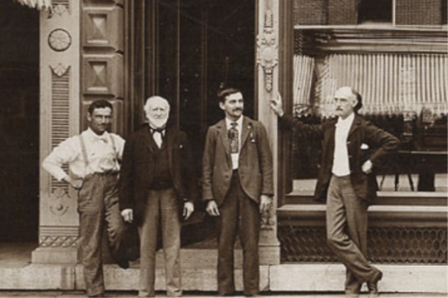 An old photo of four men in front of the bank