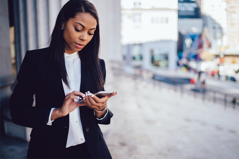 A professional woman in a business suit checking her phone.