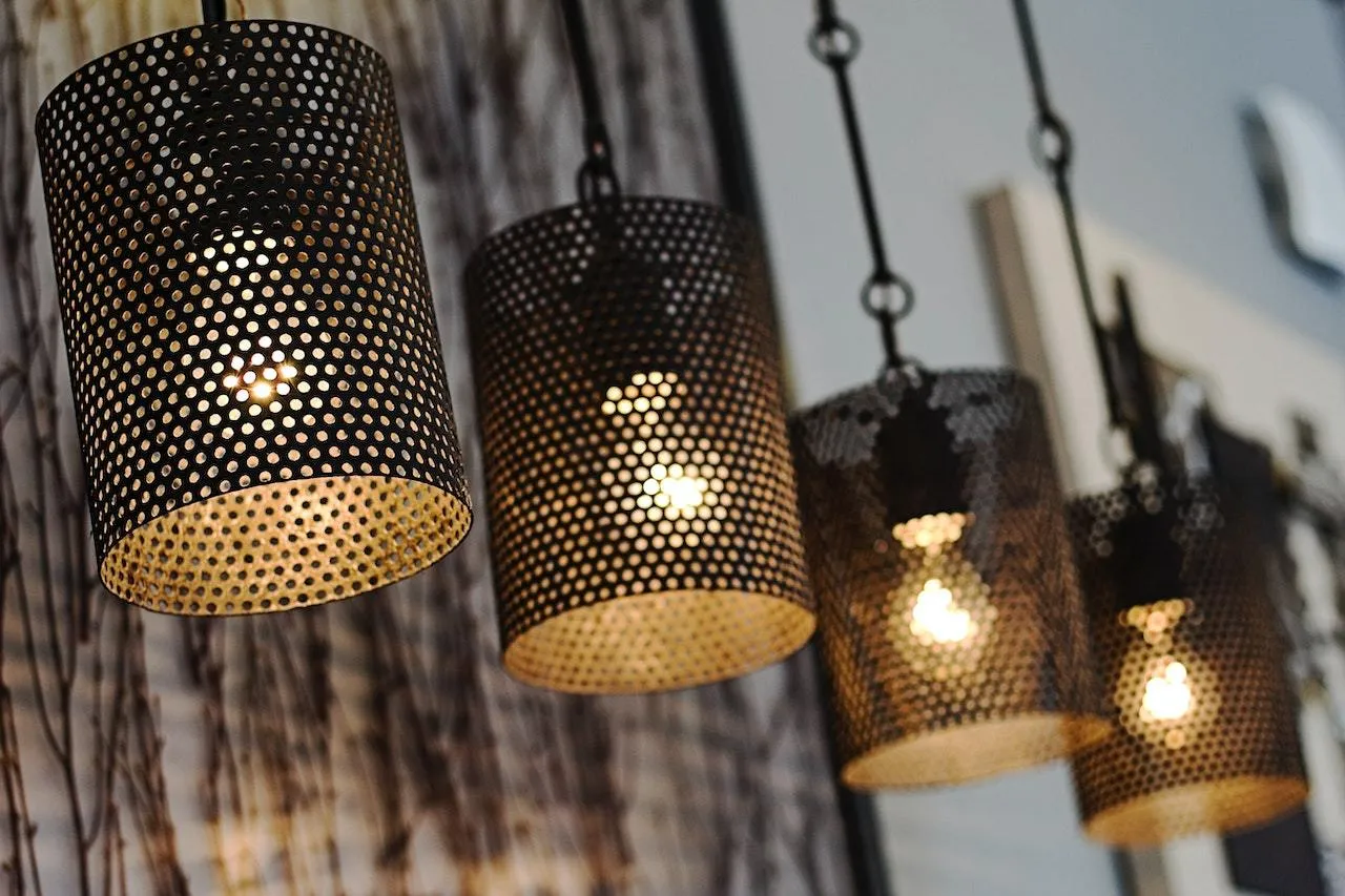 Four hanging pendant lights with perforated metal shades, each glowing with a visible bulb.