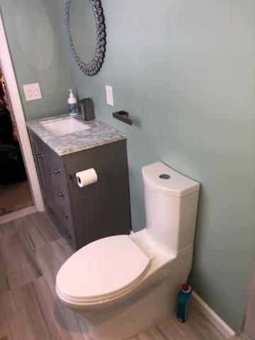 updated bathroom after renovation with dark accents and light teal wall