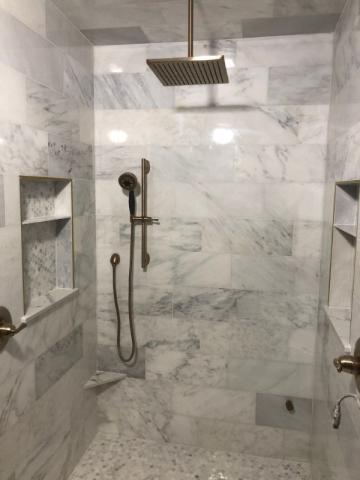 white marvle tiled shower with rainforest shower head and handheld shower head