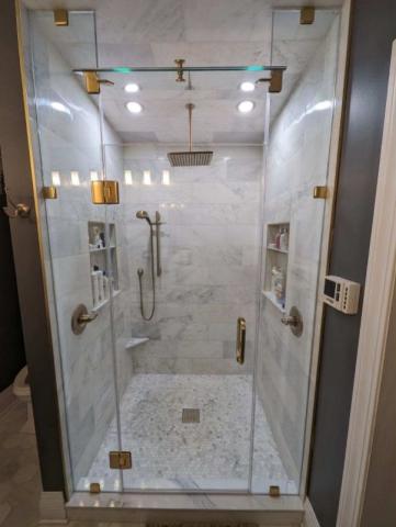 beautiful updated shower with marble tile and gold accents