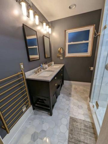 updated bathroom with darker blue walls marble countertops and gold accents